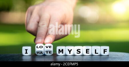 Hand turns dice and changes the expression 'I hate myself' to 'I love myself'. Stock Photo