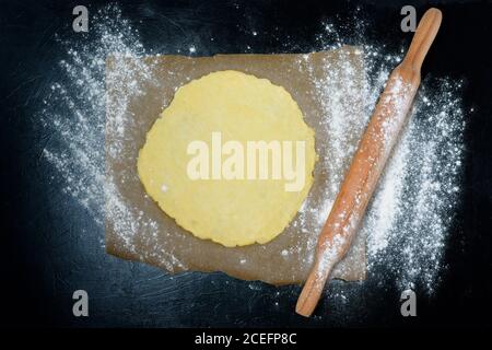 rolling pin for dough with flour scattered on a dark background. top view, close-up, space for text . preparation for making dough at home. Stock Photo
