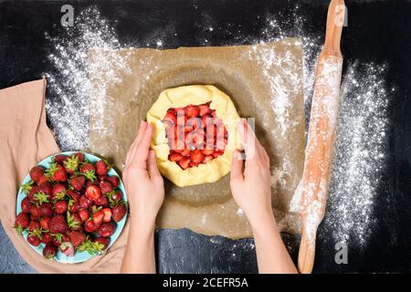 step by step recipe the process of making galetta with strawberries at home, top view on a dark background, ingredients for strawberry pie. Stock Photo