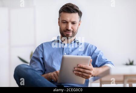 Portrait Of Handsome Young Man Using Digital Tablet During Break In Office Stock Photo