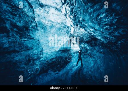 View of traveler walking in crack of beautiful crystal blue ice cave, Iceland Stock Photo