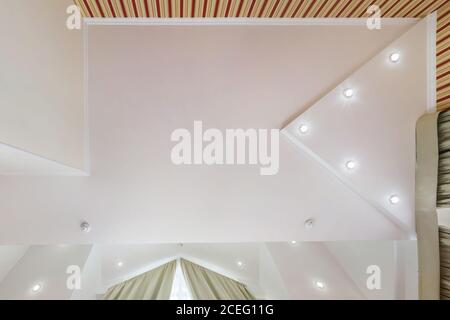 suspended ceiling with halogen spots lamps and drywall construction in empty room in apartment or house. Stretch ceiling white and complex shape. Stock Photo