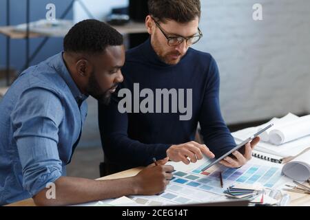 Multiracial engineer team working in office with tablet PC. Architects select colors for building using color swatches, sketching and planning Stock Photo