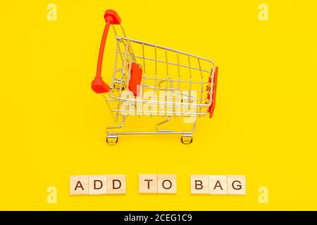 Word CART made from wooden cubes on yellow background with toys shopping cart Stock Photo