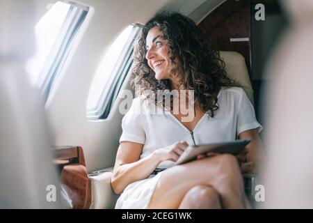 Pretty Woman works with tablet on airplane. Stock Photo