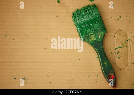 old brush stained with green paint on brown paper sheet Stock Photo