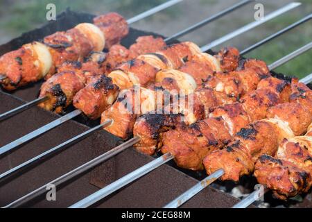 Photo cooking fry shish kebab,BBQ, barbecue, shashlik or meat on coals. Cooking meat in the grill on skewers in nature in the summer on a picnic. Pork Stock Photo