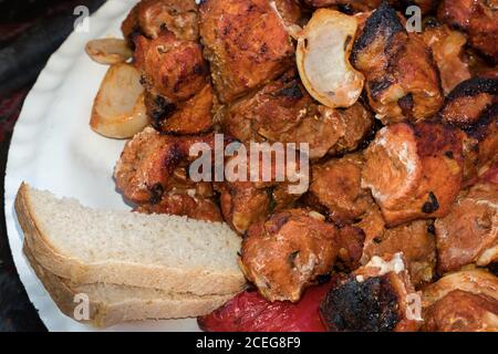 Pieces of fried meat lie on a plate with bread. Grilled shish kebab, barbecue or grill on a plate. Stock Photo