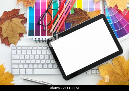 On table there is a keyboard with tablet glasses autumn leaves and colored polish. Stock Photo