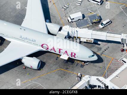 Qatar Airways Boeing 777 at Los Angeles (USA) Airport terminal connected to jet bridges for efficient boarding process. Inbound from Doha, Qatar. Stock Photo