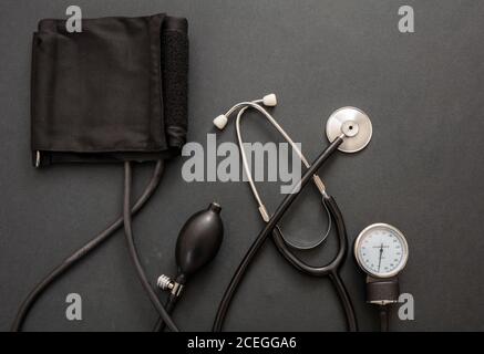 Blood pressure measure equipment, Hypertension control. Medical stethoscope and sphygmomanometer on black color background, top view. Stock Photo