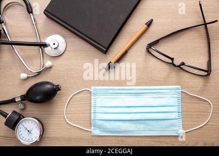 Medical stethoscope sphygmomanometer and protective mask on cardiologist doctor office desk. Coronavirus protection, healthcare concept, top view Stock Photo