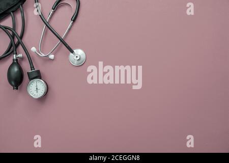 Blood pressure measure equipment, Hypertension control. Medical stethoscope and sphygmomanometer on pastel purple color background, top view. Stock Photo