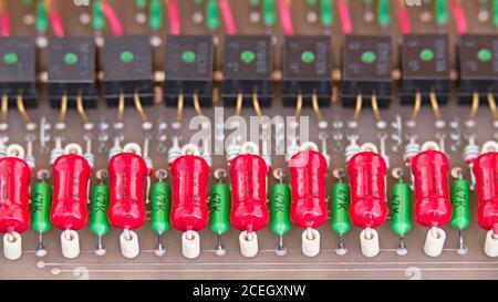 Old electronic components on retro circuit board of a galvanic isolation of data links. Obsolete red or green power resistors and black opto-isolators. Stock Photo