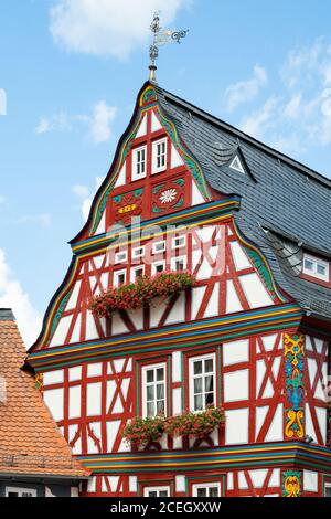 Traditional half timbered house painted red with red geraniums in window boxes in Idstein, Hesse, Germany Stock Photo
