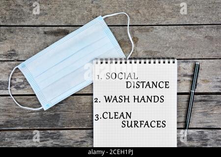 Health concept: Social distancing wash hands clean surfaces written on notebook page Stock Photo