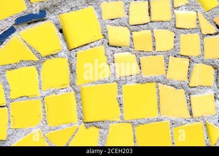Mosaic of broken yellow small tiles tiles as background. Stock Photo