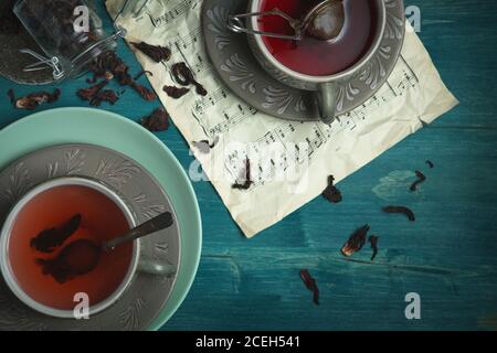Flat Lay. Dark and Moody, Mystic Light food photography. Pomegranate tea. Brewing tea. Still life of two cups of tea in a dim evening light. 5 o'clock Stock Photo