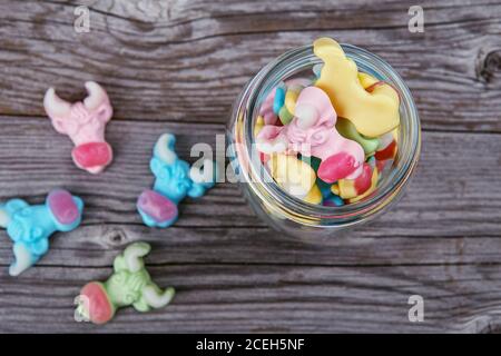 colorful neon gummy a cow candies in glass jar on the wooden texture background Stock Photo