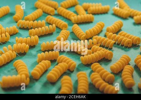 Top view of fusilli pasta on the bright blue green background. Fashion food Stock Photo