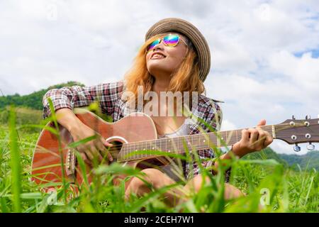 Happy woman plays guitar with nature background. Stock Photo
