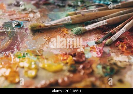 artists brushes and oil paints on wooden palette. Artist paintbrushes over palette with oil colors. palette with paintbrush and palette-knife Stock Photo