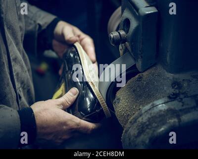unrecognizable man using polishing machine on sole of stylish footwear in workshop Stock Photo