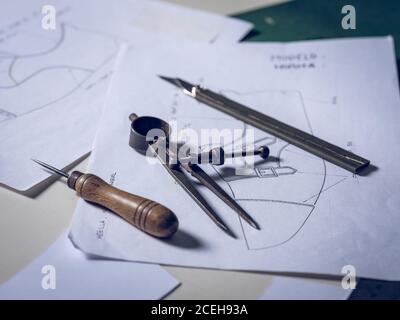 Set of various shoe making tools lying on shoe sketches on table in workshop Stock Photo