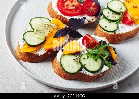 Variety of sandwiches with cream cheese, tomato, cucumber, basil, arugula and lemon. Stock Photo