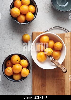 Ripe yellow mirabelle plums in bowls. Making jam, top view. Stock Photo
