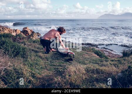 Young man cleaning surf board Stock Photo