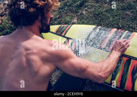 Young man cleaning surf board Stock Photo