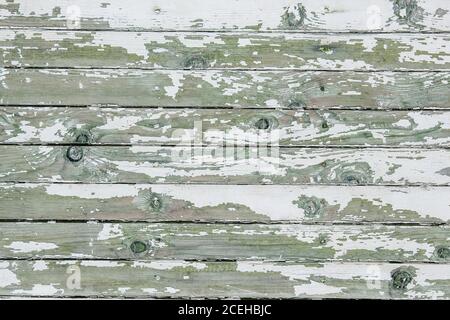 Cracking and peeling white paint on a wall. Vintage wood background with peeling paint. Old board with Irradiated paint Stock Photo