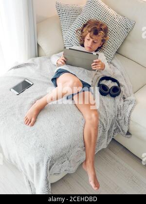 Cheerful boy using tablet of couch Stock Photo