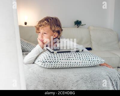 Cute boy with tablet on sofa Stock Photo