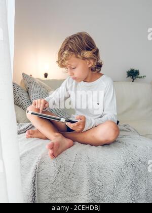 Cute boy with tablet on sofa Stock Photo