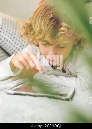 boy using tablet on sofa Stock Photo