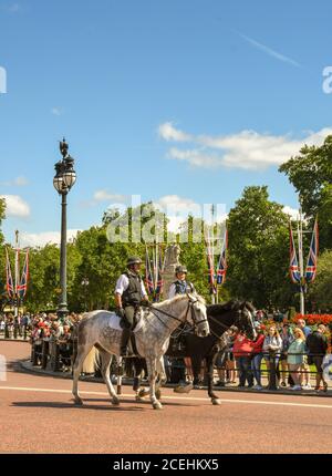 London, England - July 2018: Two police horses the road outside Buckingham Palace, with people gathered for the changing of the guard ceremony. Stock Photo