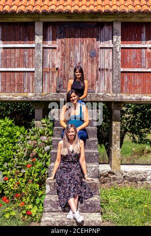 Three friends sitting on an horreo, a structure designed to keep rats, mice, and other animals away from the stored grain, on the rural areas of Galic Stock Photo