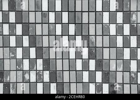 texture of old wall tiles with peeling gray paint. grey old shabby tiles background. Black and white photography Stock Photo