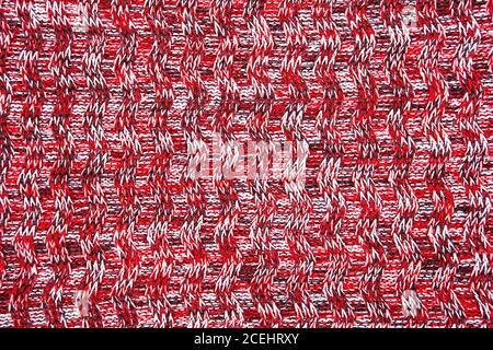 Wool scarf or sweater texture close up. Red Knitted jersey background with a relief pattern. Braids in machine knitting pattern Stock Photo