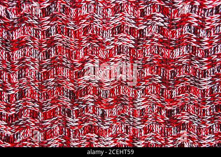 Wool scarf or sweater texture close up. Red Knitted jersey background with a relief pattern. Braids in machine knitting pattern Stock Photo