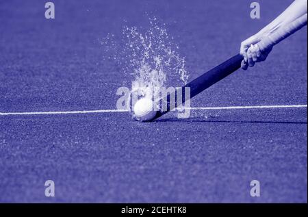 Hockey player with ball in attack playing field hockey game. Blue color filter Stock Photo