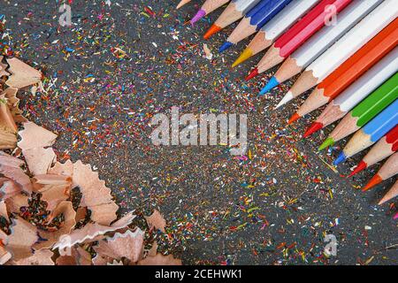close up shot of colored pencil crayons and pencil crayons shavings on dark background. Sharpened colored pencils Stock Photo