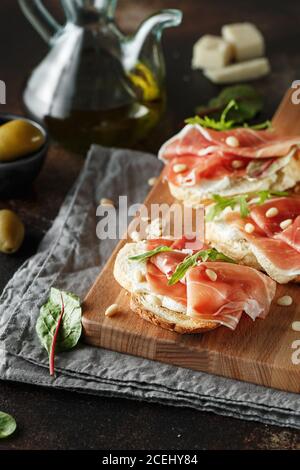 Traditional parma cured ham antipasto. Bruschetta set with Parma Ham and Parmesan Cheese. Small sandwiches with prosciutto, parmesan cheese, fresh aru Stock Photo