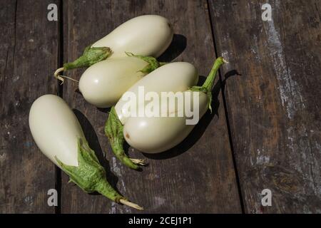 White aubergines on an old wooden textural background. Fresh eggplants Stock Photo