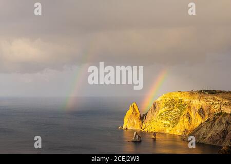 Scenic view from Jasper beach near St. George Monastery to Cape Fiolent in rainy day with rainbow. Rocky coast black sea and cliff, Sevastopol, Crimea Stock Photo