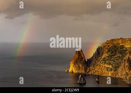 Scenic view from Jasper beach near St. George Monastery to Cape Fiolent in rainy day with rainbow. Rocky coast black sea and cliff, Sevastopol, Crimea Stock Photo