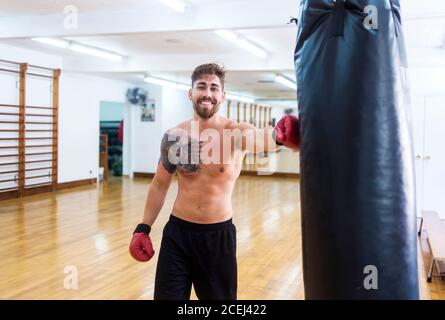 Portrait of a young boxer leaning on the punch bag at the gym Stock Photo