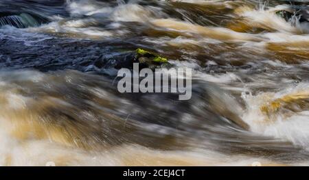 Running water in chaos with the sun illuminating the water among rocks in Vattenfallet which is located in Älvkarleby Sweden Stock Photo